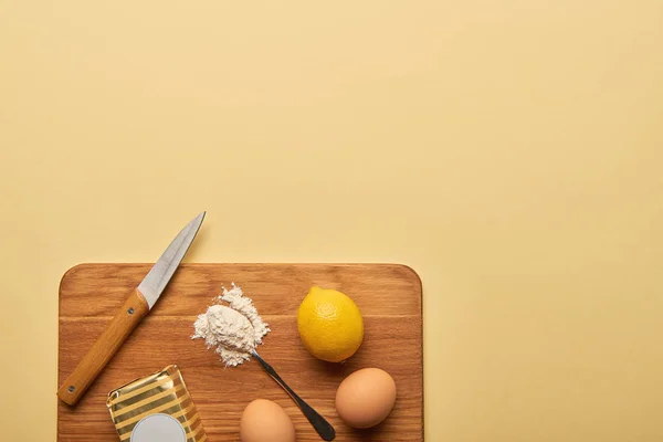 Draufsicht auf Zutaten und Messer auf Holzschneidebrett auf gelbem Hintergrund mit Kopierraum — Stockfoto