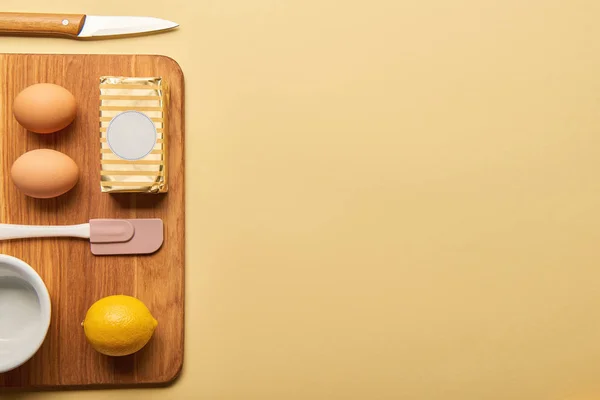 Flat lay with knife, spatula and ingredients on wooden chopping board — Stock Photo