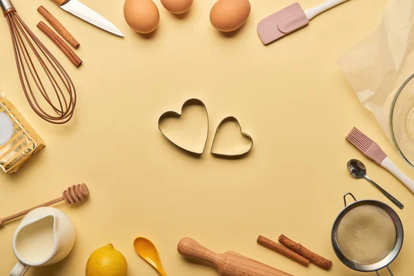 Вид зверху на хлібобулочні інгредієнти та кухонне начиння навколо форми тіста у формі серця — стокове фото