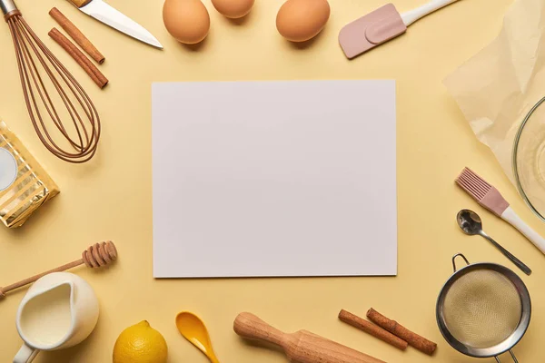 Vista superior de los ingredientes de la panadería y utensilios de cocina alrededor de la tarjeta en blanco - foto de stock