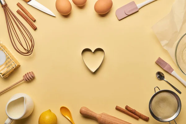 Vista dall'alto di ingredienti da forno e utensili da cucina intorno a stampo di pasta a forma di cuore — Foto stock