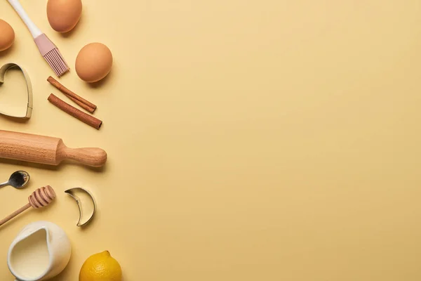 Vista superior de ingredientes de padaria e utensílios de cozinha com moldes de massa no fundo amarelo com espaço de cópia — Fotografia de Stock