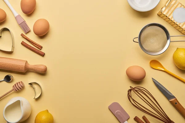 Vista superior de los ingredientes de la panadería y utensilios de cocina sobre fondo amarillo - foto de stock