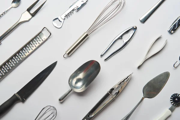 Flat lay with shiny metal cooking utensils on grey background — Stock Photo