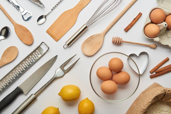 Flat lay com utensílios de cozinha de metal e madeira e produtos crus em fundo cinza — Fotografia de Stock