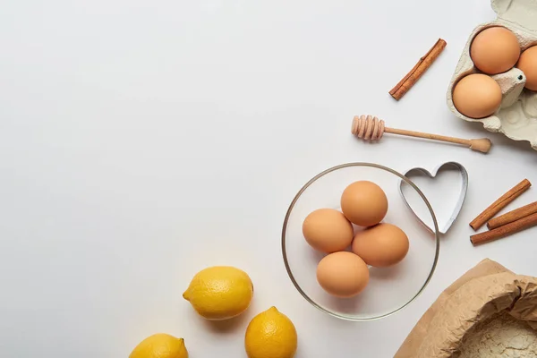 Vista superior de los ingredientes de la panadería y molde de masa en forma de corazón sobre fondo gris - foto de stock