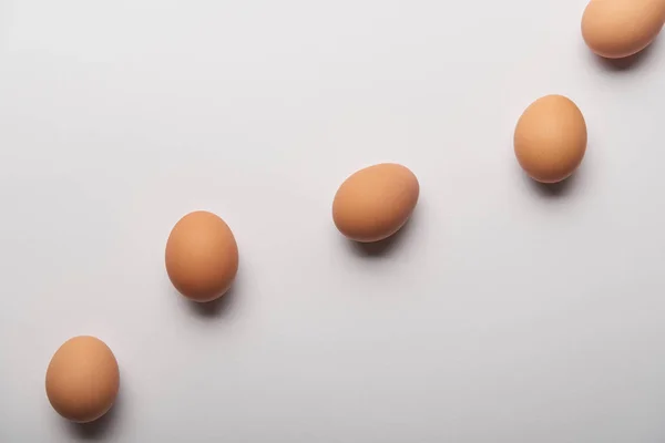 Ansicht von Bio-Eiern in geschwungener Linie auf grauem Hintergrund — Stockfoto