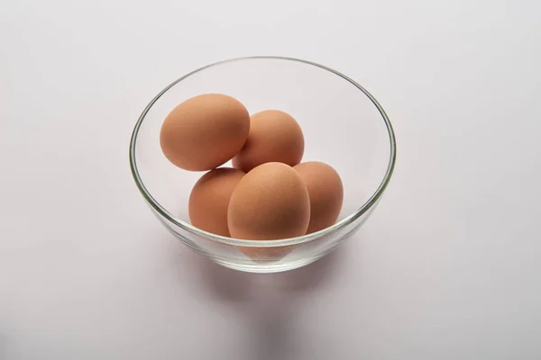 Eggs in transparent glass bowl on grey surface — Stock Photo