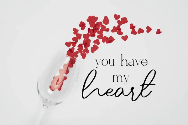 Top view of wine glass and small paper cut hearts on white background with 