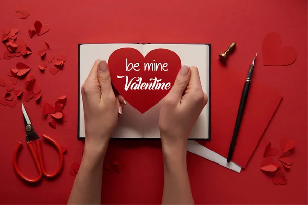 Cropped view of woman holding paper cut heart sign with 