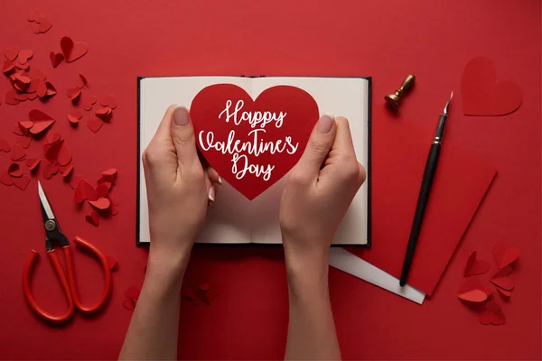 Cropped view of woman holding paper cut heart sign with 