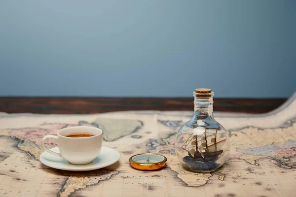 Foco seletivo de copo de café, bússola e brinquedo navio em garrafa de vidro no mapa com espaço de cópia — Fotografia de Stock