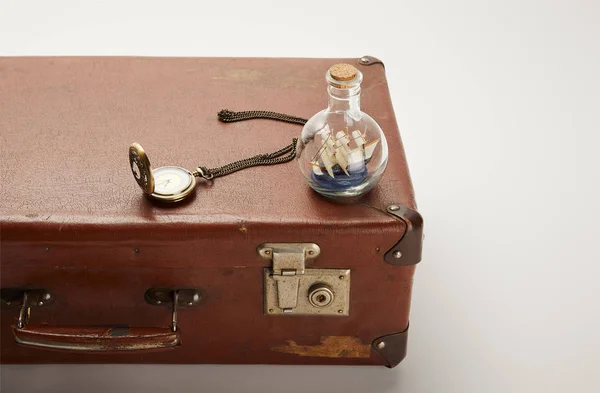 Toy ship in glass bottle and compass on brown suitcase with copy space — Stock Photo