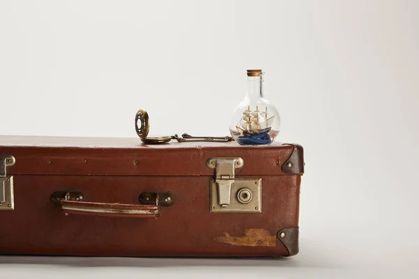 Toy ship in glass bottle and compass on vintage brown suitcase with copy space — Stock Photo