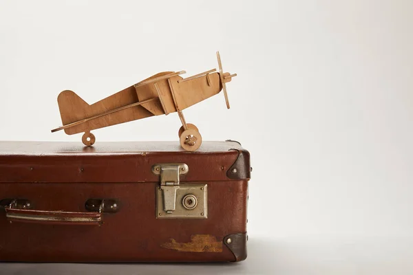 Avião de brinquedo e mala de couro em fundo cinza com espaço de cópia — Fotografia de Stock