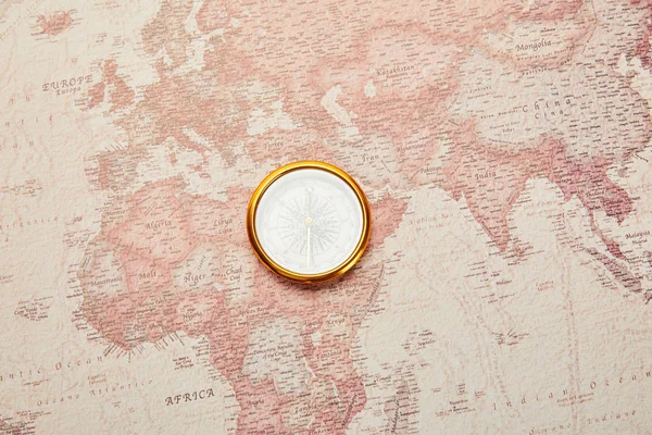 Vista superior de la brújula dorada en el mapa del mundo vintage - foto de stock