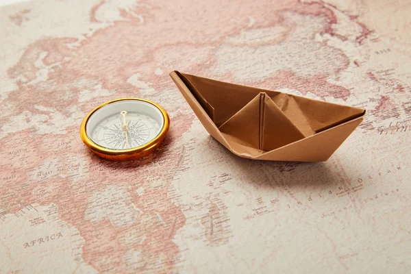 Brújula dorada y barco de papel en el mapa del mundo retro - foto de stock