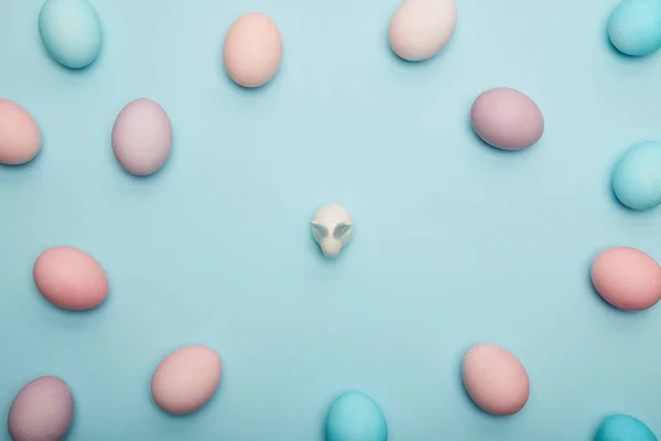 Vista superior de huevos de Pascua y conejito de juguete sobre fondo azul - foto de stock