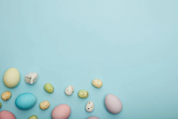 Top view of toy bunny, easter chicken and perail eggs on blue background — стоковое фото