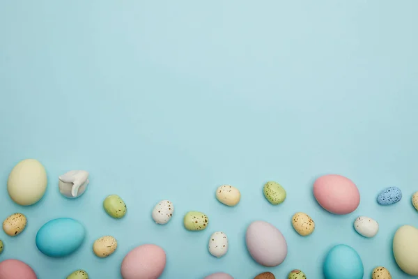 Вид зверху на іграшковий кролик, великоднє куряче яйце та перепелині яйця на синьому фоні з космічним простором — стокове фото