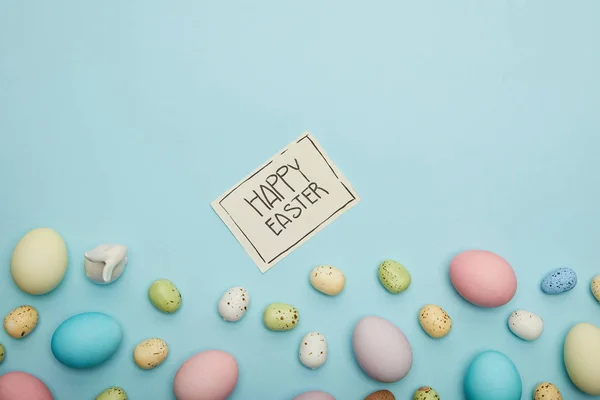 Vue du dessus du lapin jouet, du poulet de Pâques et des œufs de caille, carte avec lettrage de Pâques heureux — Photo de stock