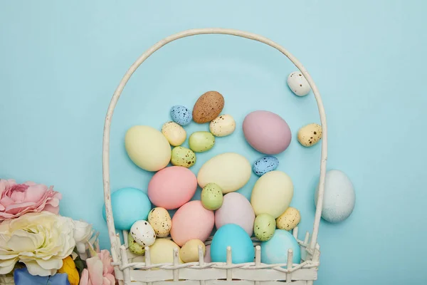 Top view of easter chicken and quail eggs in straw basket and flowers — Stock Photo
