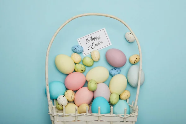 Vista superior de ovos de galinha e codorniz pintados em cesta de palha, cartão com letras felizes da páscoa — Fotografia de Stock