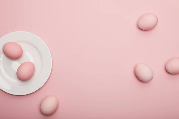 Top view of painted easter eggs on plate on pink background — Stock Photo