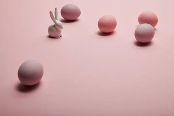 Coniglietto giocattolo e uova di Pasqua dipinte su sfondo rosa — Foto stock