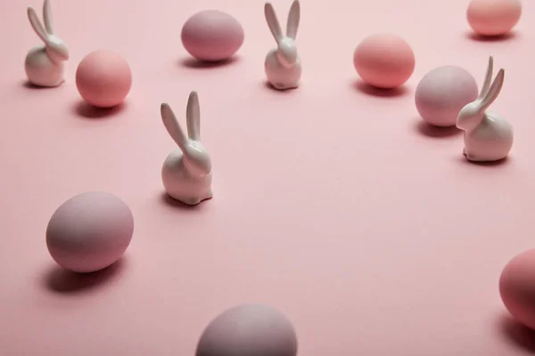 Toy bunnies and painted easter eggs on pink background — Stock Photo