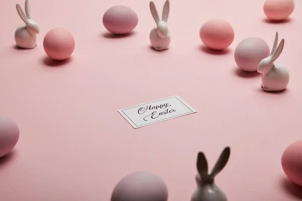 Toy bunnies, card with happy easter lettering and painted easter eggs on pink background with copy space — Stock Photo