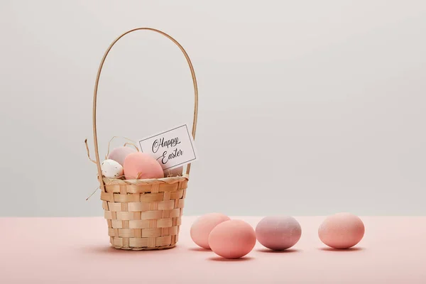 Easter chicken and quail egg in straw basket, card with happy easter lettering on grey background — Stock Photo