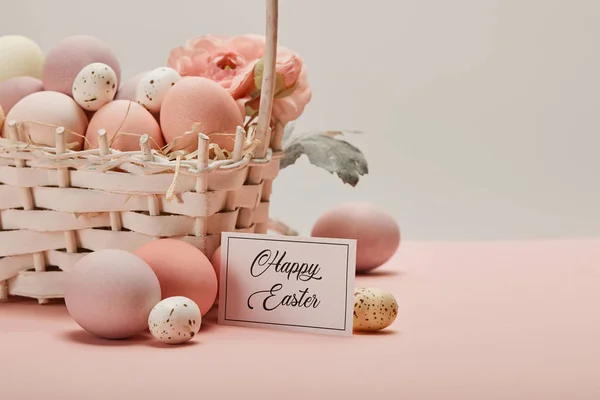 Easter chicken and quail eggs in straw basket with flower and card with happy easter lettering — Stock Photo