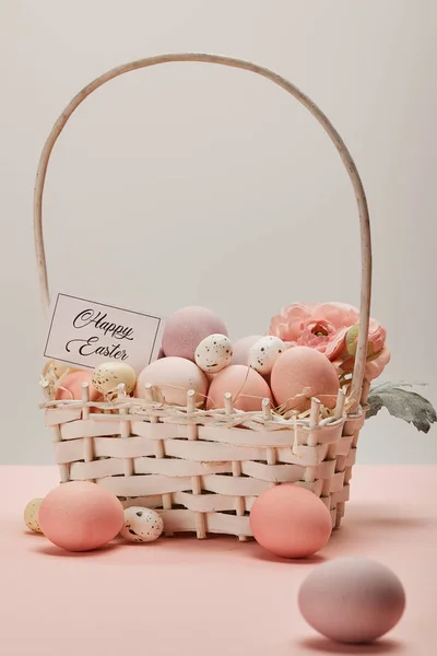 Easter chicken and quail eggs in straw basket with flower and card with happy easter lettering — Stock Photo