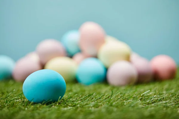 Foyer sélectif des œufs de Pâques sur l'herbe sur fond bleu — Photo de stock