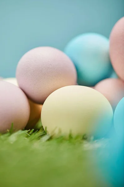 Primer plano de huevos de Pascua pintados sobre hierba y sobre fondo azul - foto de stock