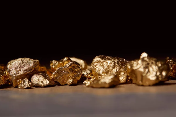 Золоті камені на мармуровому столі ізольовані на чорному — стокове фото