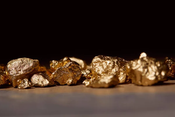 Piedras doradas sobre mesa de mármol aislado en negro - foto de stock