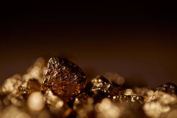 Foco seletivo de pedras douradas com fundo borrado e preto — Fotografia de Stock