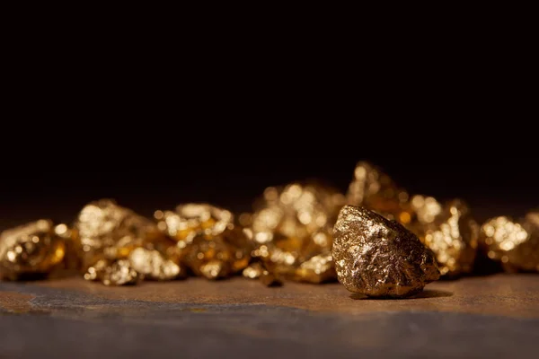 Selective focus of golden stones on dark marble isolated on black — Stock Photo