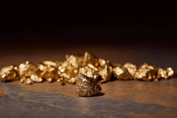 Вибірковий фокус золотих каменів на мармуровому та чорному розмитому фоні — стокове фото