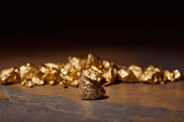 Selective focus of golden stones on marble and black blurred background — Stock Photo