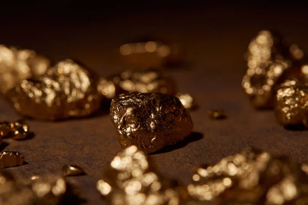 Selektiver Fokus der goldenen Steine auf braunem Marmorhintergrund — Stockfoto