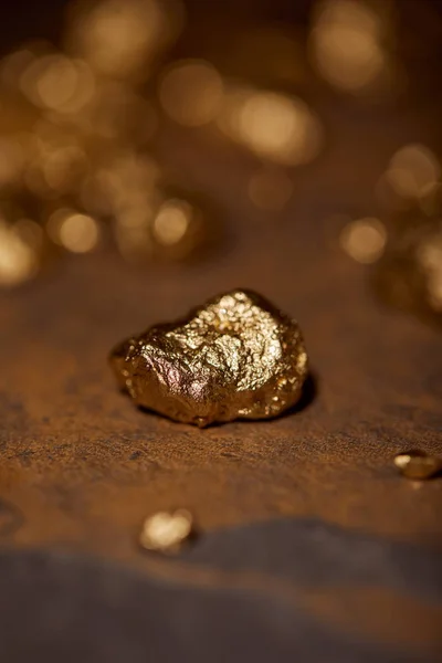 Selective focus of golden stone on brown marble surface and blurred background — Stock Photo