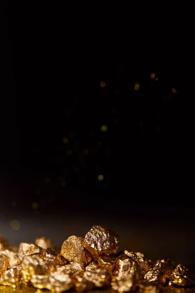 Golden stones on dark surface with sparkling lights on black background — Stock Photo