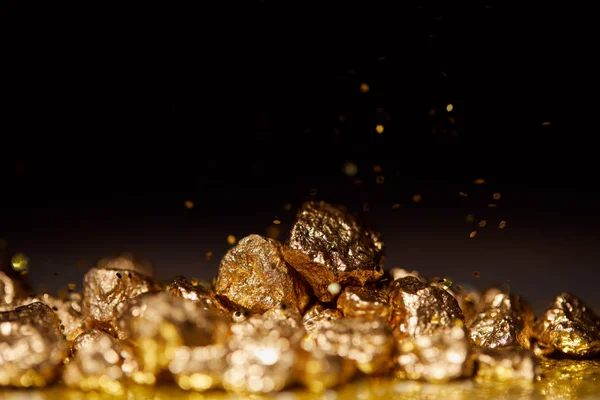 Golden stones on sparkling surface and black background — Stock Photo