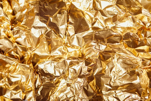 Zerknittertes goldenes Folienblatt mit leuchtenden Glitzern — Stockfoto