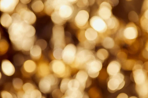 Bright blurred golden twinkles and sparkles on dark background — Stock Photo