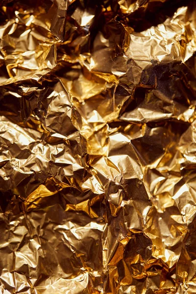 Folha de folha dourada amassada com brilhantes brilhos e sombras — Fotografia de Stock