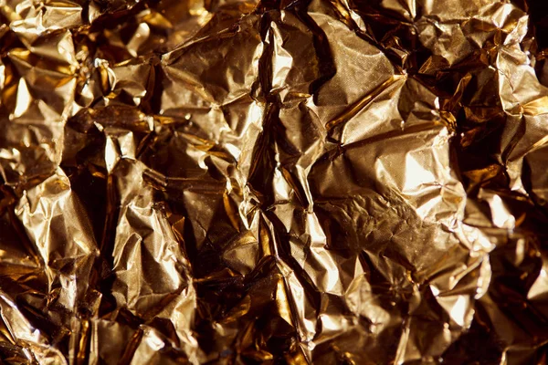 Creased golden foil sheet with twinkles and shadows — Stock Photo